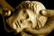 Sepia photograph of two hands cradling a carved stone head